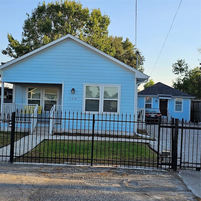 bungalow-style home with a fenced front yard and covered porch