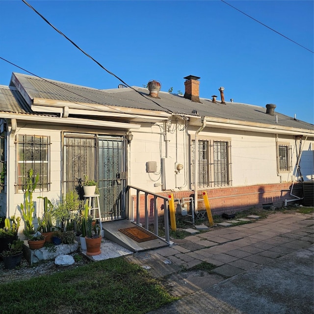 back of property featuring a patio, concrete block siding, and a chimney