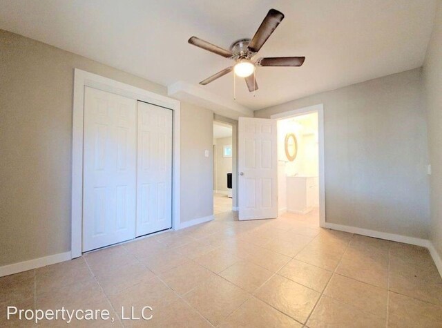 unfurnished bedroom featuring a ceiling fan, light tile patterned floors, baseboards, and a closet