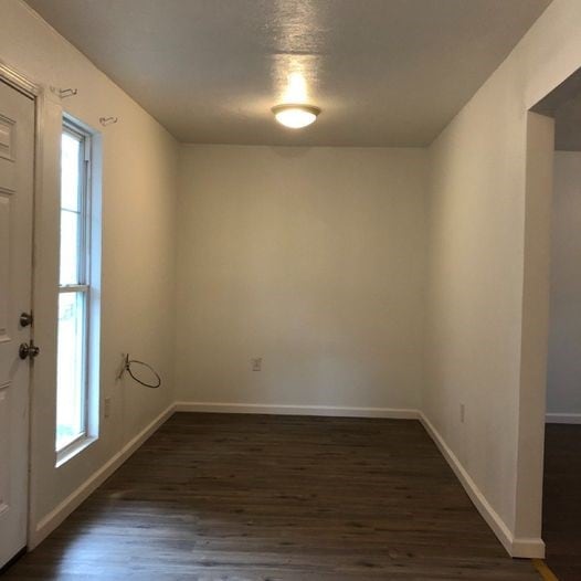 interior space featuring baseboards and dark wood-style flooring