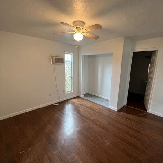 empty room with baseboards, a textured ceiling, a ceiling fan, and hardwood / wood-style flooring