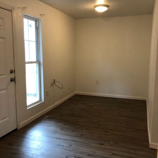 empty room featuring baseboards and dark wood-type flooring