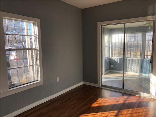 spare room with dark wood finished floors, a ceiling fan, and baseboards