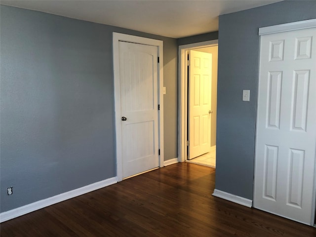 spare room with dark wood-type flooring and baseboards