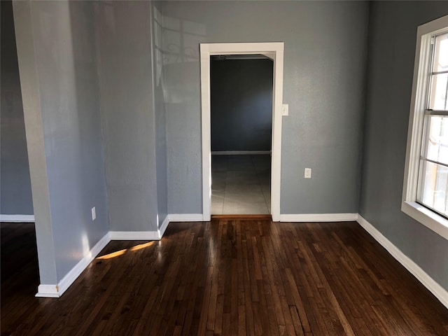 empty room featuring baseboards and dark wood-style floors