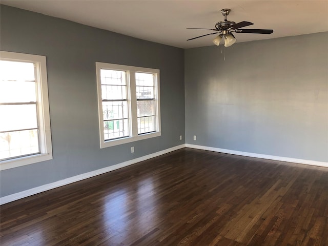 empty room with baseboards, dark wood finished floors, and a ceiling fan