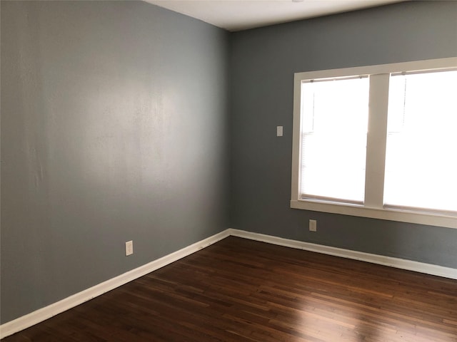 unfurnished room with dark wood-type flooring and baseboards