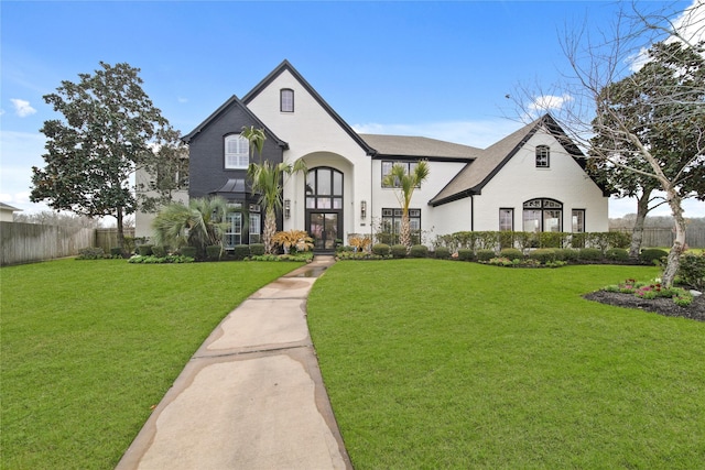 french provincial home featuring a front yard, french doors, and fence