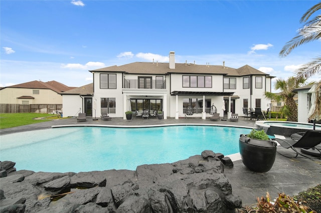 view of pool with a patio, fence, and a pool with connected hot tub