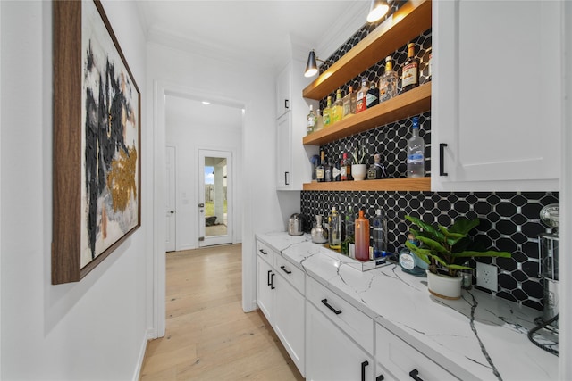 bar featuring decorative backsplash, crown molding, and light wood-type flooring