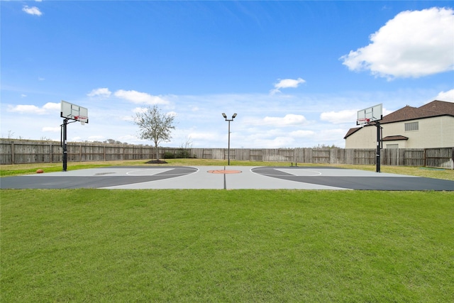 view of sport court featuring basketball court, a lawn, and fence