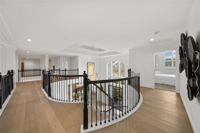 corridor with a wealth of natural light, an upstairs landing, visible vents, and light wood finished floors