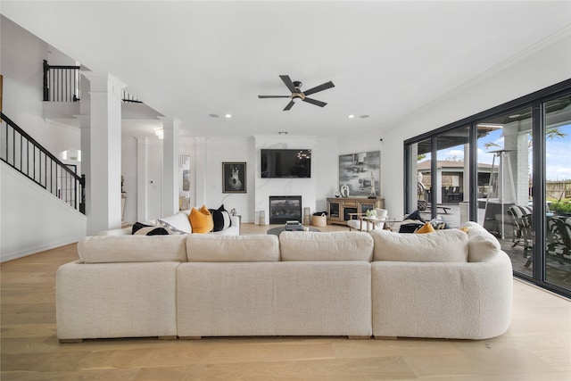 living room with ceiling fan, stairs, light wood-type flooring, decorative columns, and recessed lighting