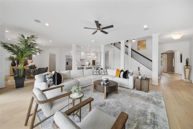 living area with stairway, recessed lighting, light wood-style floors, arched walkways, and ornate columns