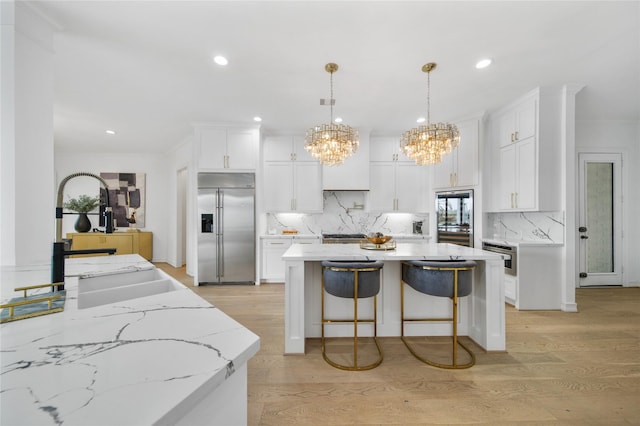 kitchen with a sink, a center island, light wood finished floors, and stainless steel built in fridge