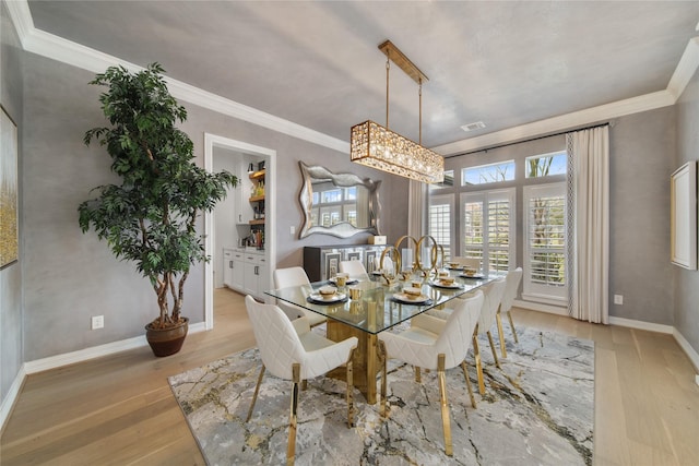 dining area featuring visible vents, crown molding, light wood-type flooring, and baseboards