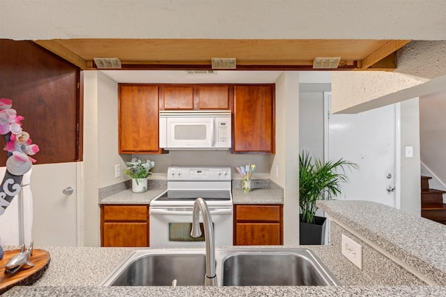 kitchen with a sink, white appliances, brown cabinetry, and light countertops