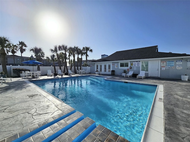 community pool featuring french doors, fence, and a patio area