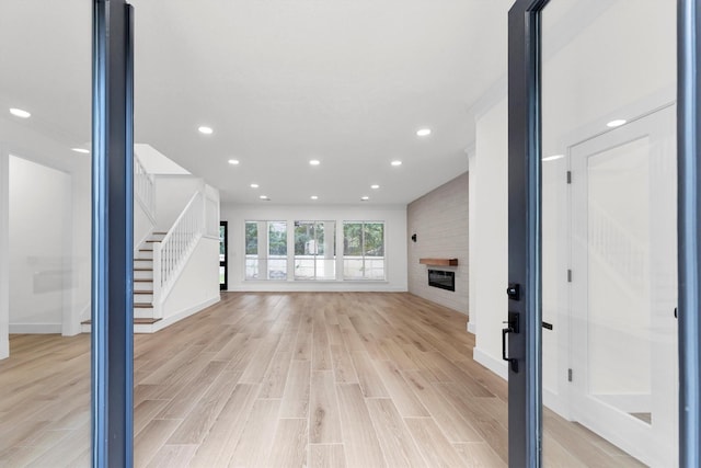 unfurnished living room with stairs, light wood-style floors, recessed lighting, and a fireplace