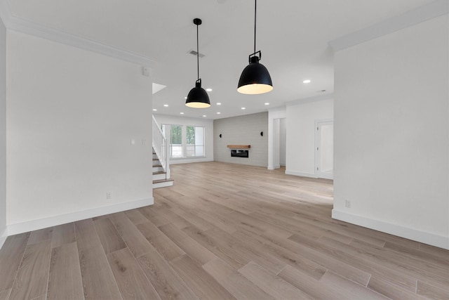 unfurnished living room featuring baseboards, recessed lighting, a fireplace, stairs, and light wood-style floors