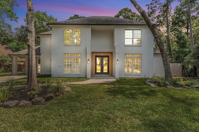 view of front of house with french doors, brick siding, a front lawn, and fence