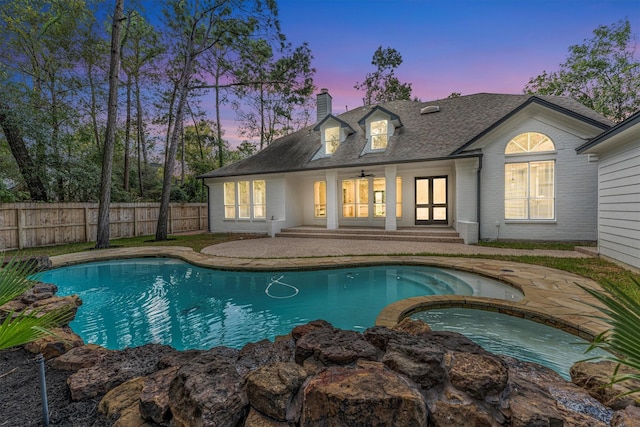 view of swimming pool with a ceiling fan, a pool with connected hot tub, a patio, fence, and french doors