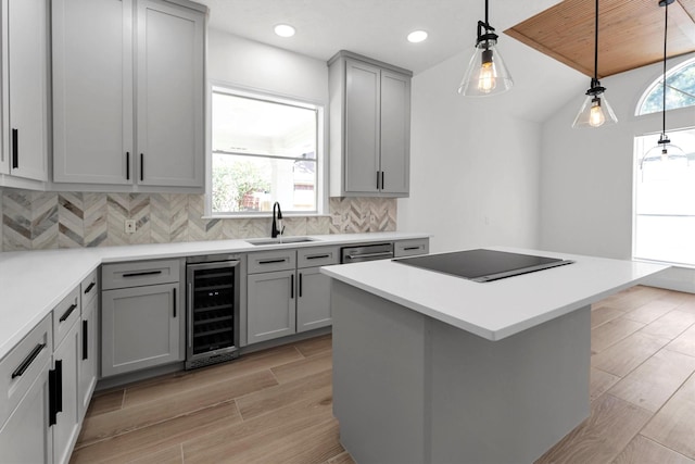 kitchen with gray cabinets, a sink, wine cooler, black electric cooktop, and tasteful backsplash