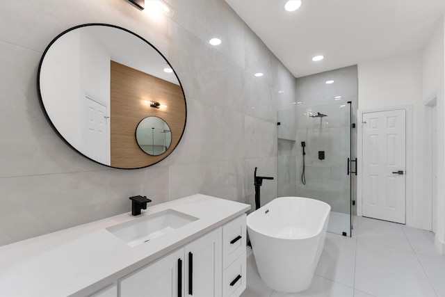 bathroom featuring vanity, recessed lighting, a stall shower, a freestanding bath, and tile walls