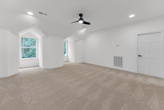 spare room featuring visible vents, baseboards, light colored carpet, lofted ceiling, and a ceiling fan