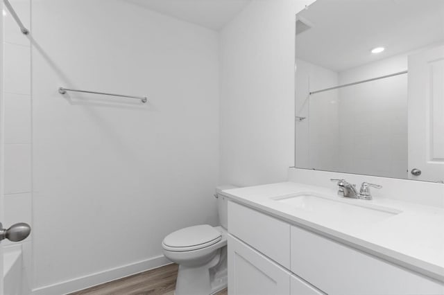 bathroom with toilet, wood finished floors, recessed lighting, baseboards, and vanity