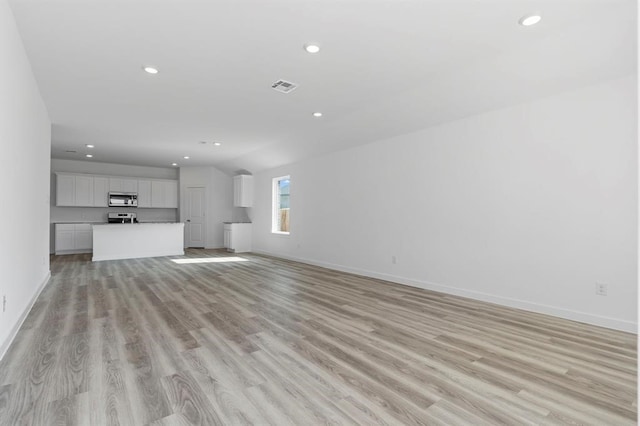 unfurnished living room featuring light wood finished floors, visible vents, recessed lighting, and baseboards