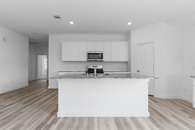 kitchen with white cabinetry, light stone countertops, a kitchen island with sink, and stainless steel appliances