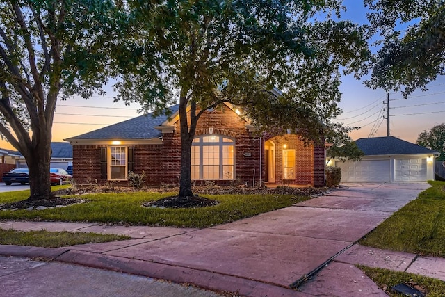 view of front of house with an outbuilding, brick siding, a detached garage, and a front lawn