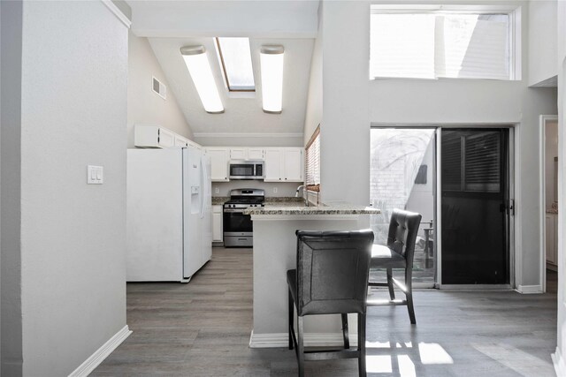 kitchen featuring light wood finished floors, visible vents, appliances with stainless steel finishes, a peninsula, and white cabinets