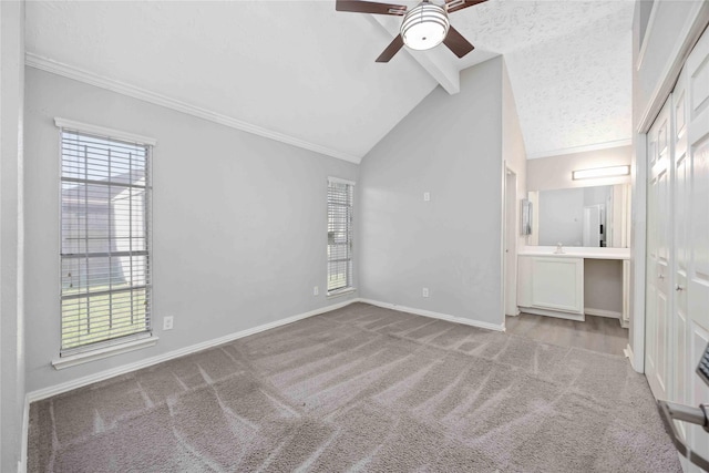 unfurnished bedroom featuring lofted ceiling with beams, multiple windows, carpet, and baseboards