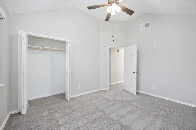 unfurnished bedroom with visible vents, a textured ceiling, carpet floors, and vaulted ceiling