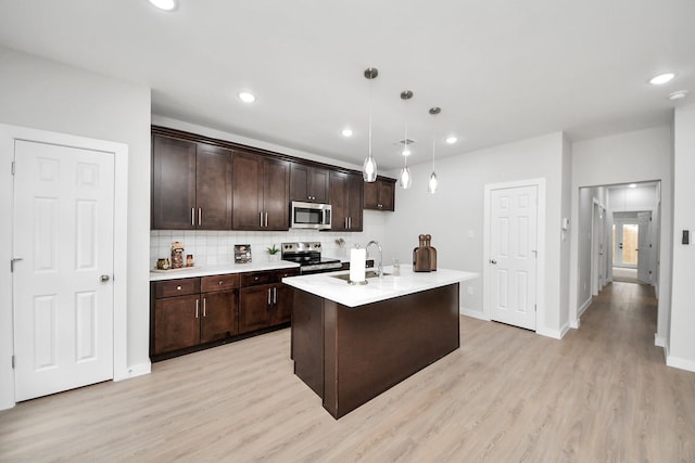 kitchen featuring tasteful backsplash, dark brown cabinetry, light countertops, light wood-style flooring, and stainless steel appliances