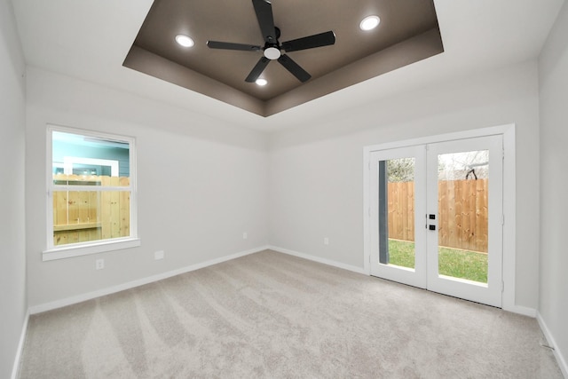 carpeted spare room with recessed lighting, french doors, a healthy amount of sunlight, and a tray ceiling