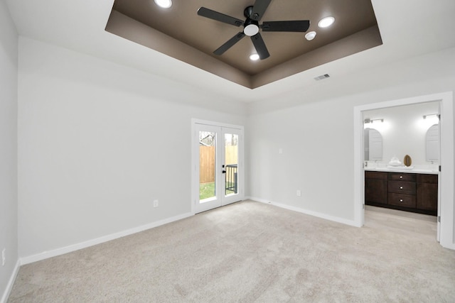 unfurnished bedroom featuring a raised ceiling, access to outside, baseboards, and light carpet