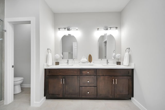 bathroom with double vanity, toilet, baseboards, and a sink