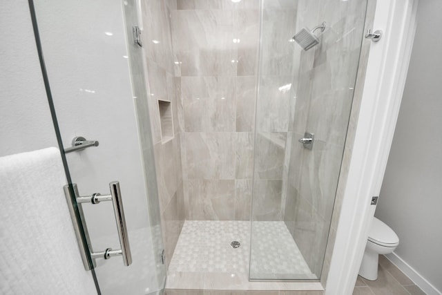 bathroom featuring tile patterned flooring, a shower stall, and toilet