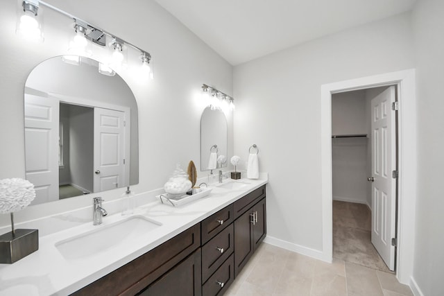 bathroom with double vanity, baseboards, tile patterned floors, and a sink