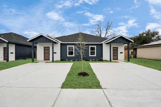 view of front of property featuring board and batten siding, a front lawn, and a shingled roof