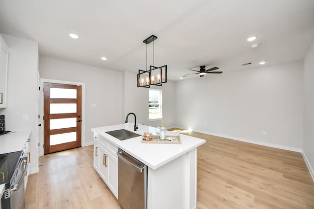 kitchen with light wood finished floors, a center island with sink, appliances with stainless steel finishes, white cabinetry, and a sink