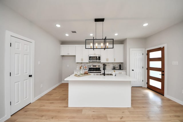 kitchen with light countertops, backsplash, light wood-style floors, and appliances with stainless steel finishes