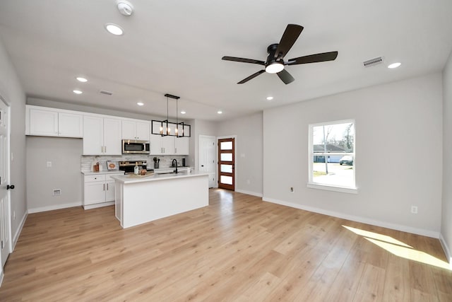 kitchen with light wood-type flooring, visible vents, tasteful backsplash, white cabinetry, and stainless steel appliances