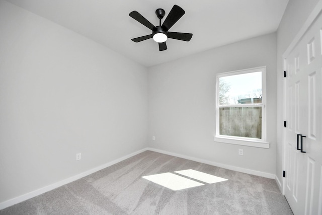 empty room with a ceiling fan, baseboards, and carpet floors