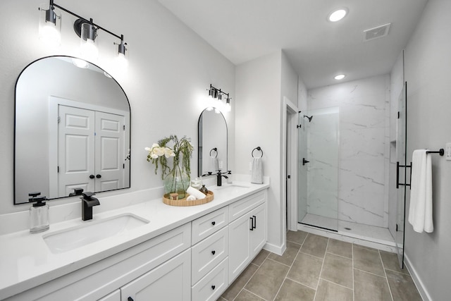 full bathroom with a marble finish shower, visible vents, double vanity, and a sink