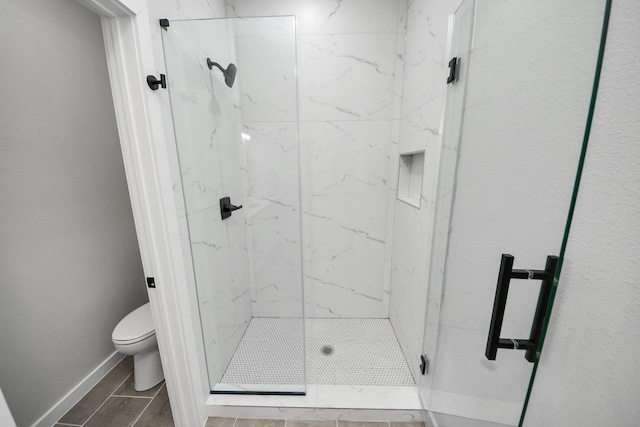 full bathroom featuring toilet, baseboards, and a marble finish shower