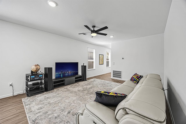 living room with a ceiling fan, wood finished floors, visible vents, and baseboards